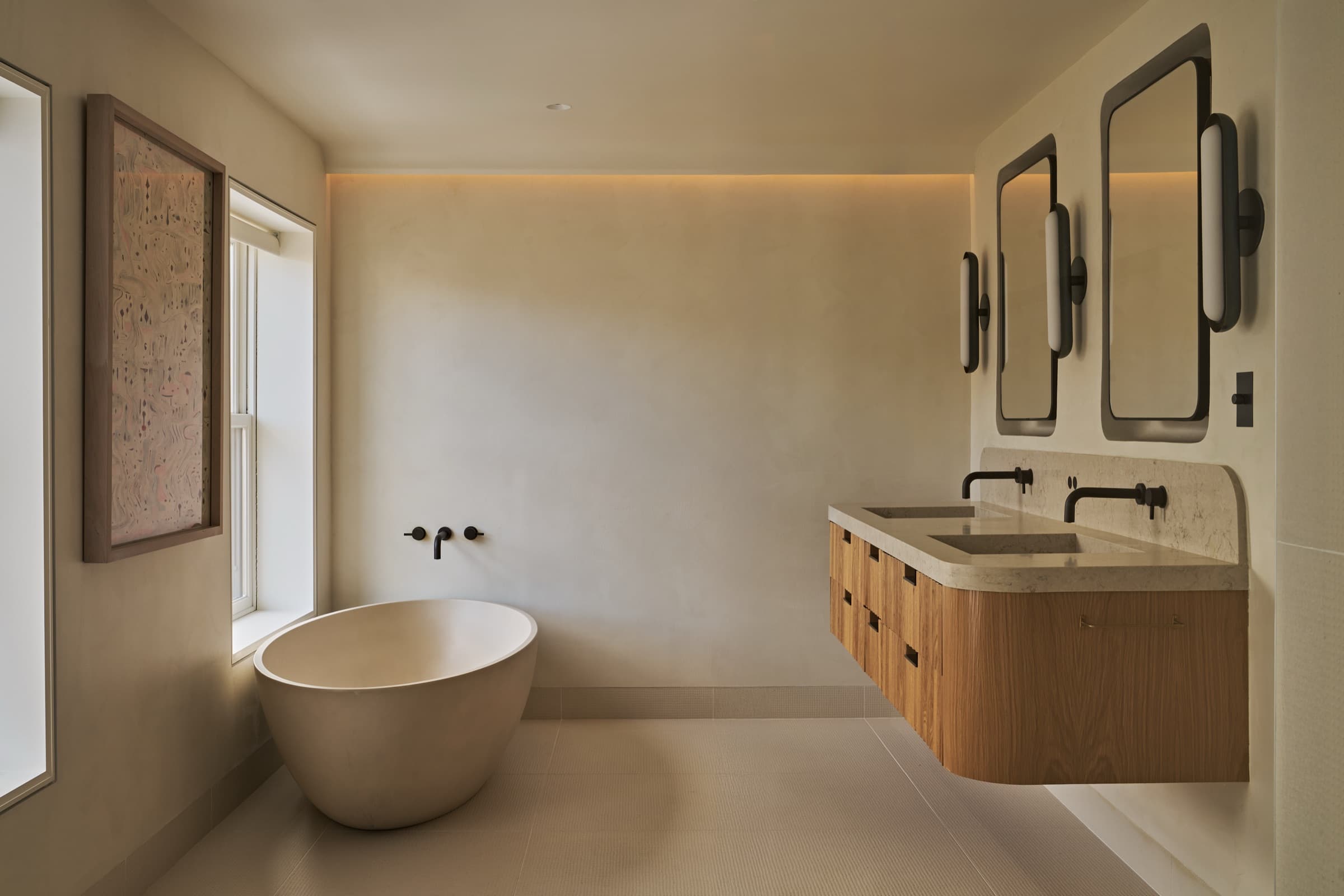 Bathroom with a freestanding soaking tub and curved floating timber vanity with stone countertop