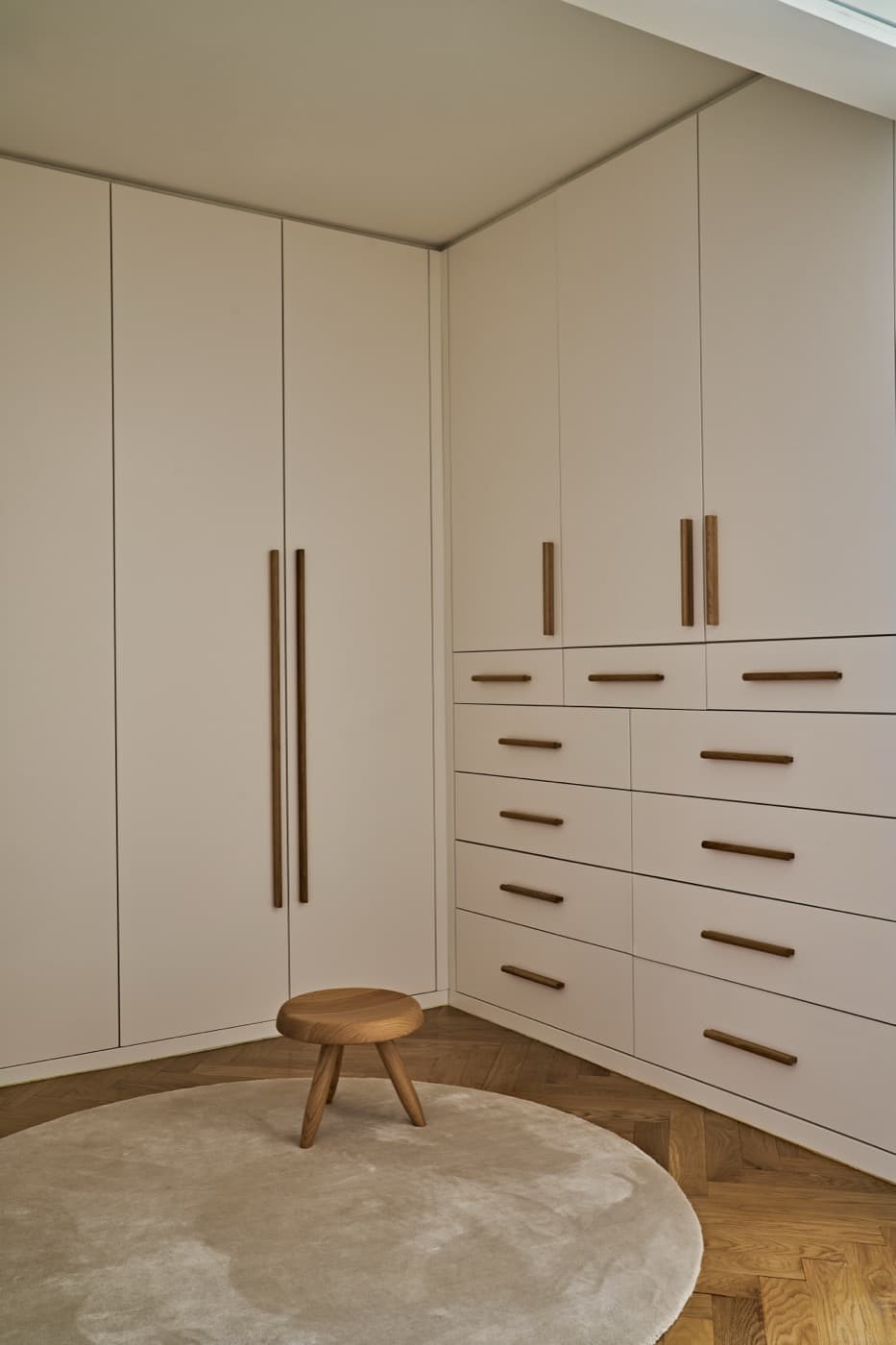 Dressing room with custom built-in full-height wardrobes and drawers featuring timber handles
