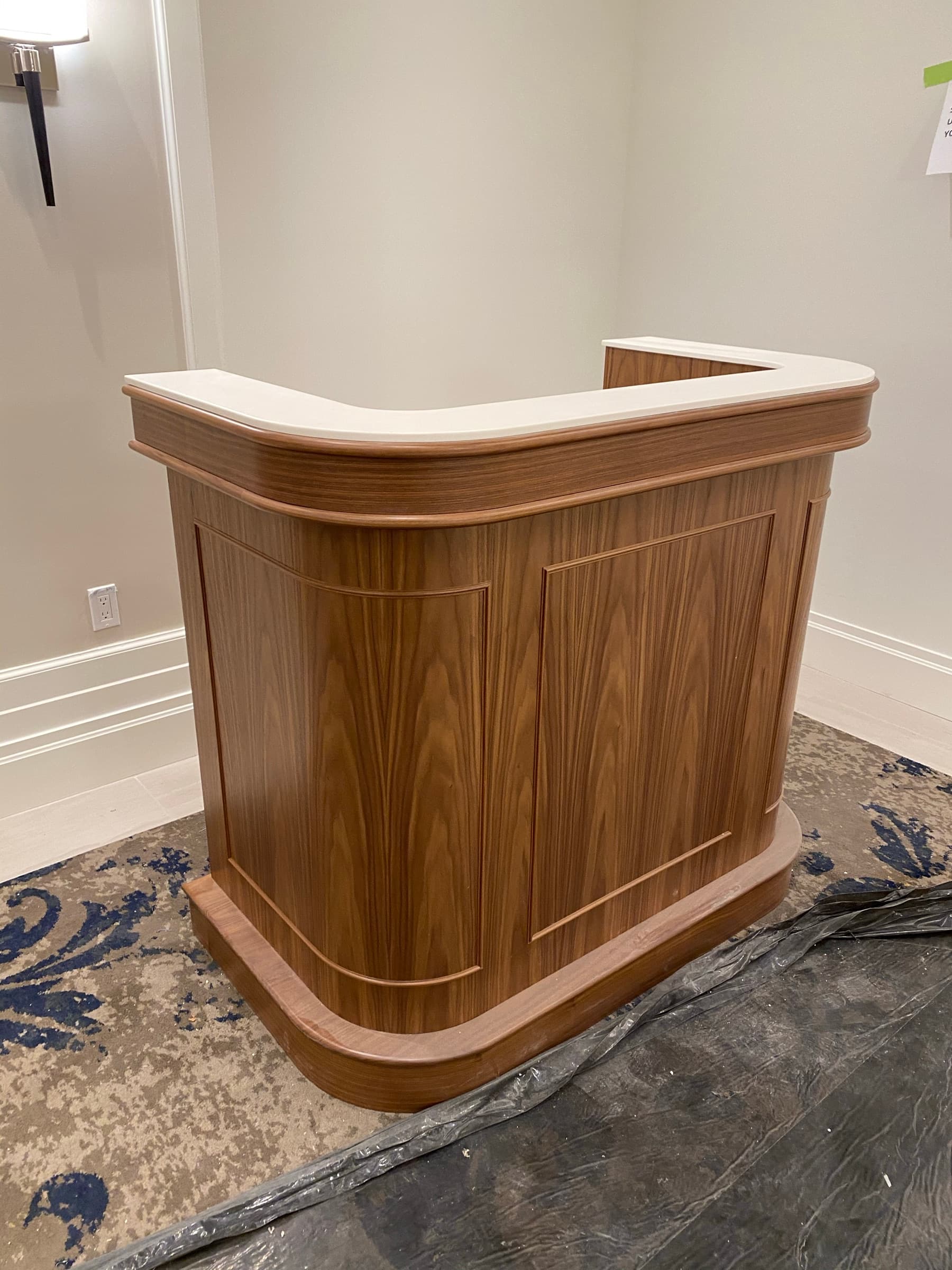Lobby featuring a curved medium-toned timber reception desk with paneled detailing and a pale countertop