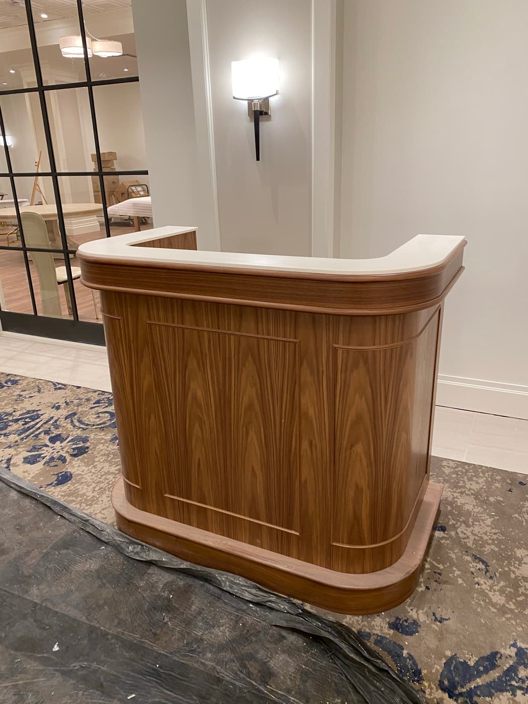Lobby featuring a custom curved timber reception podium with detailed paneling and white countertop