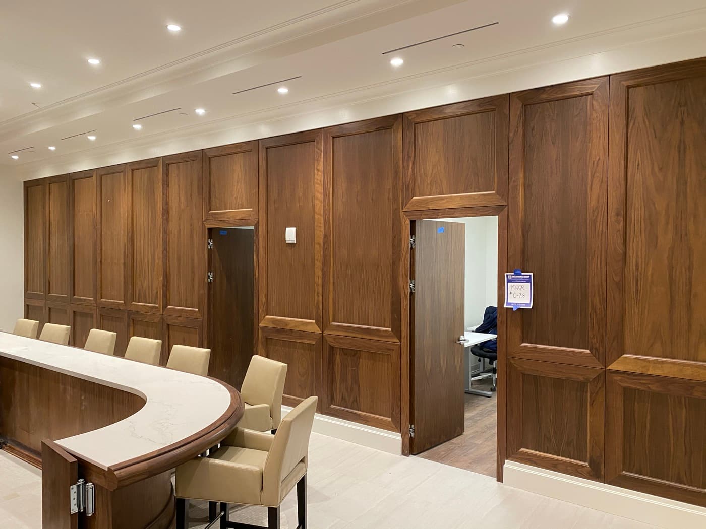 Boardroom featuring rich timber wall panelling with integrated doors and a curved stone counter