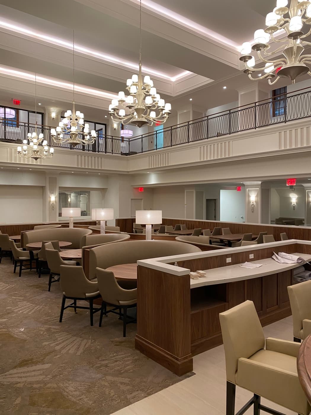 Double-height dining hall featuring custom wood banquette booths, service partitions, and tiered chandeliers