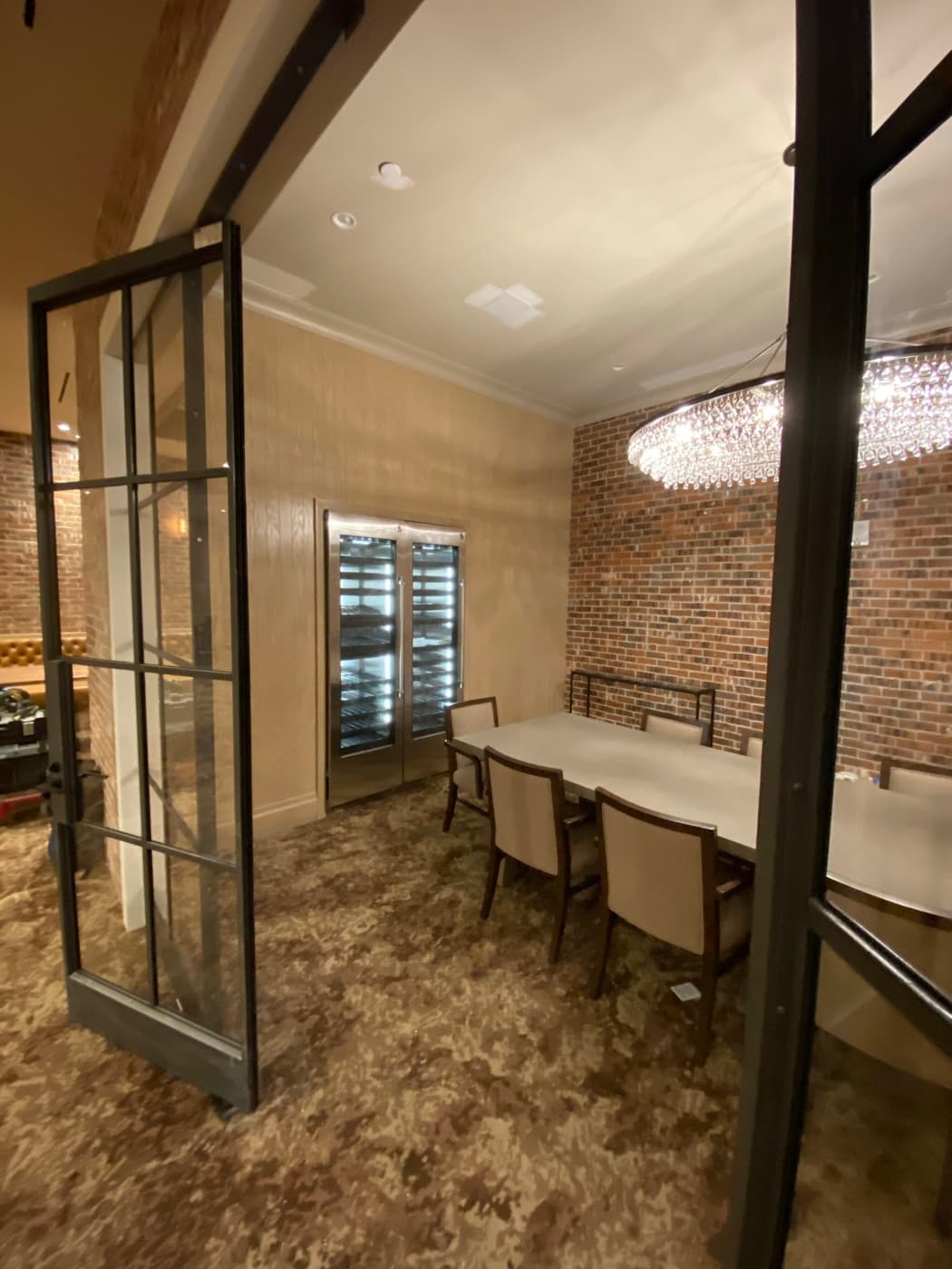 Dining room with dark metal glass doors, brick accent wall, and built-in wine refrigerators