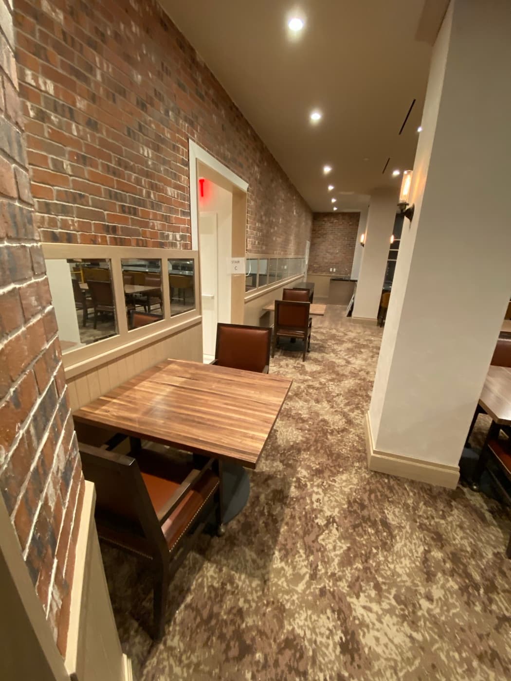Hospitality dining area featuring an exposed brick wall, timber tables, and painted wainscoting