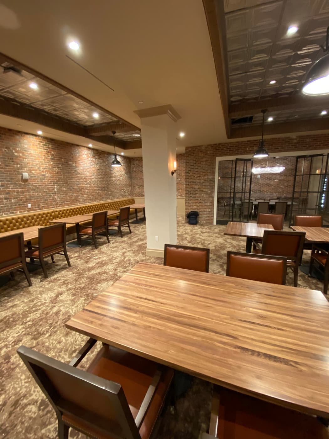 Restaurant dining space with brick walls, tufted banquette seating, and timber tables
