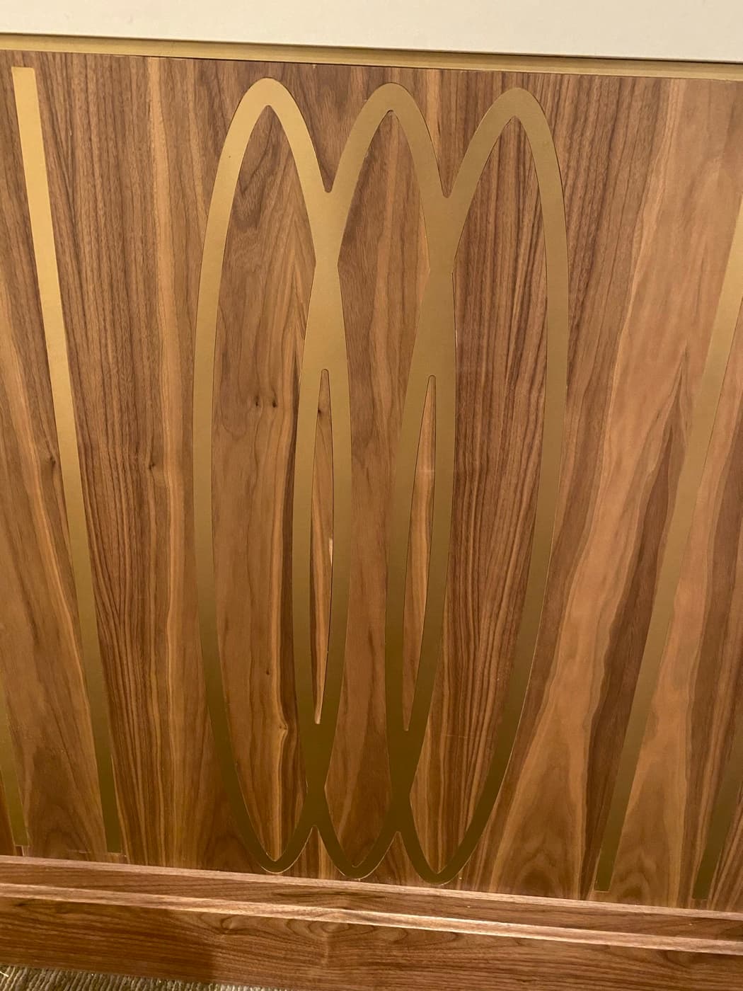 Interior detail of custom timber wall panelling with geometric brass-toned metal inlays