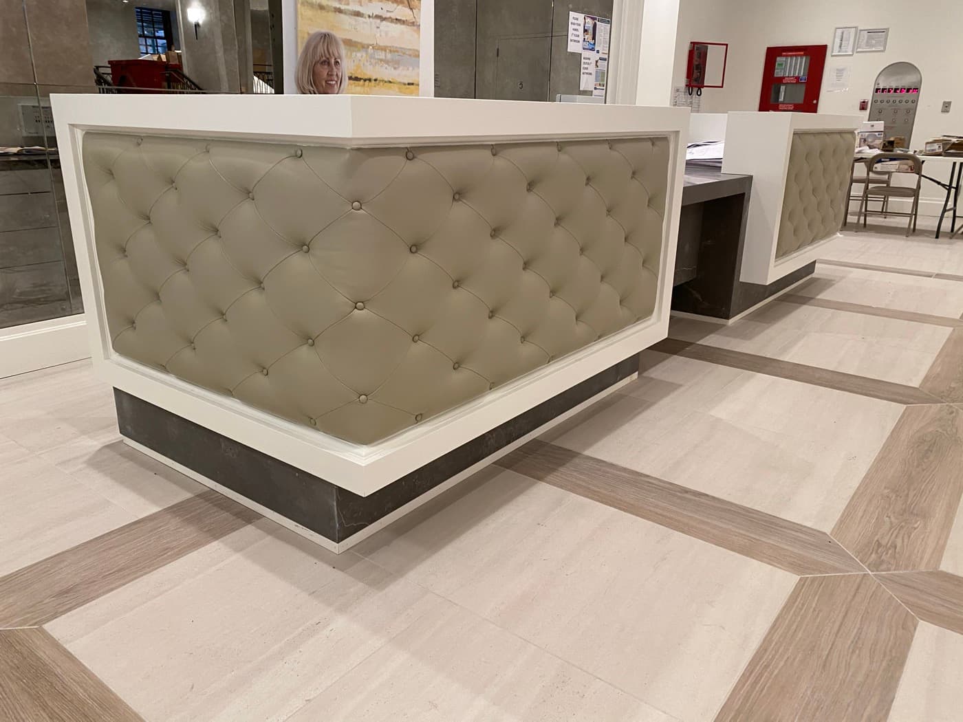 Lobby reception area featuring a custom desk with button-tufted upholstery and white millwork framing
