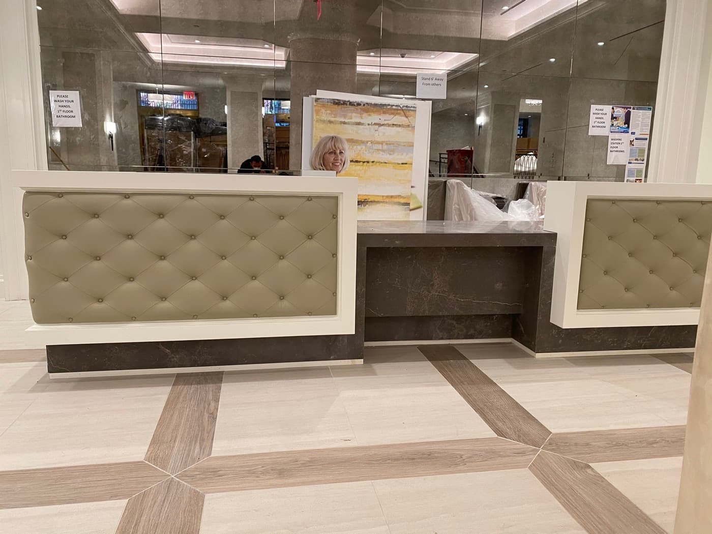 Commercial lobby reception desk featuring tufted upholstery panels, white trim, and dark stone counters