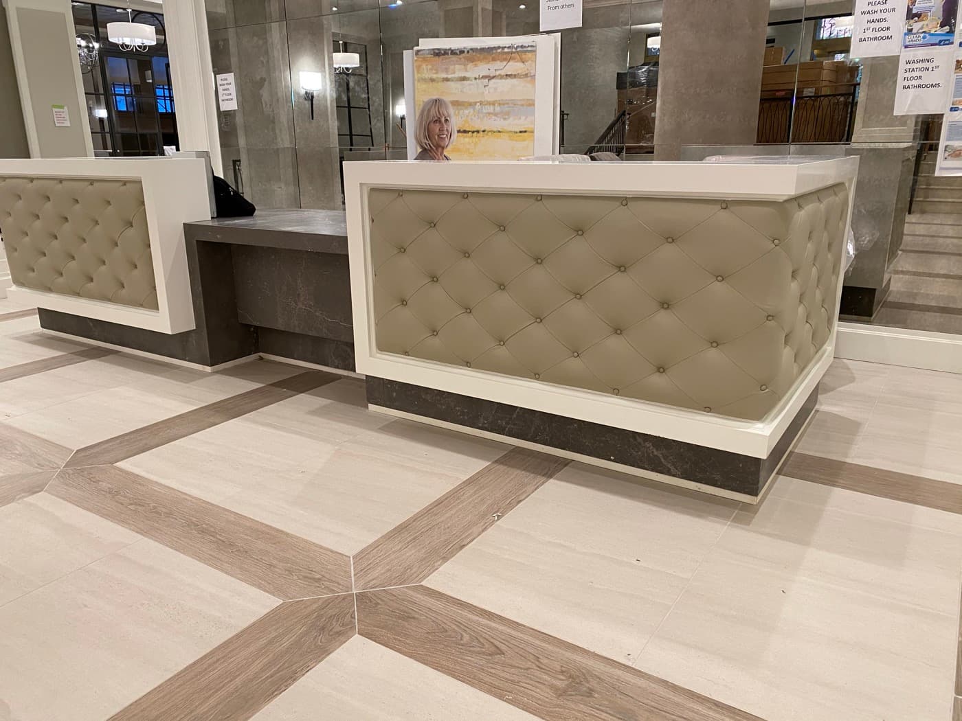 Lobby reception desk with tufted upholstered front panels, dark stone counter, and patterned tile floor