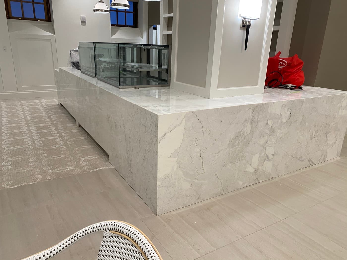 Cafe interior featuring a pale veined stone waterfall counter and glass display cases