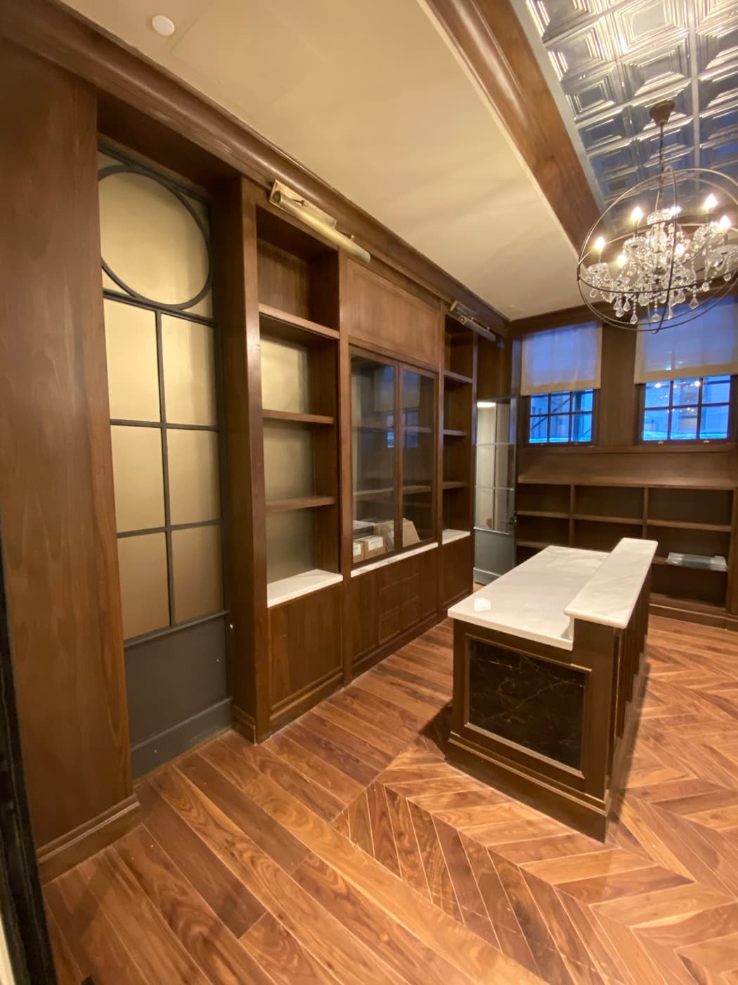 Dressing room featuring dark timber built-in cabinetry, display shelving, and a central stone-topped island