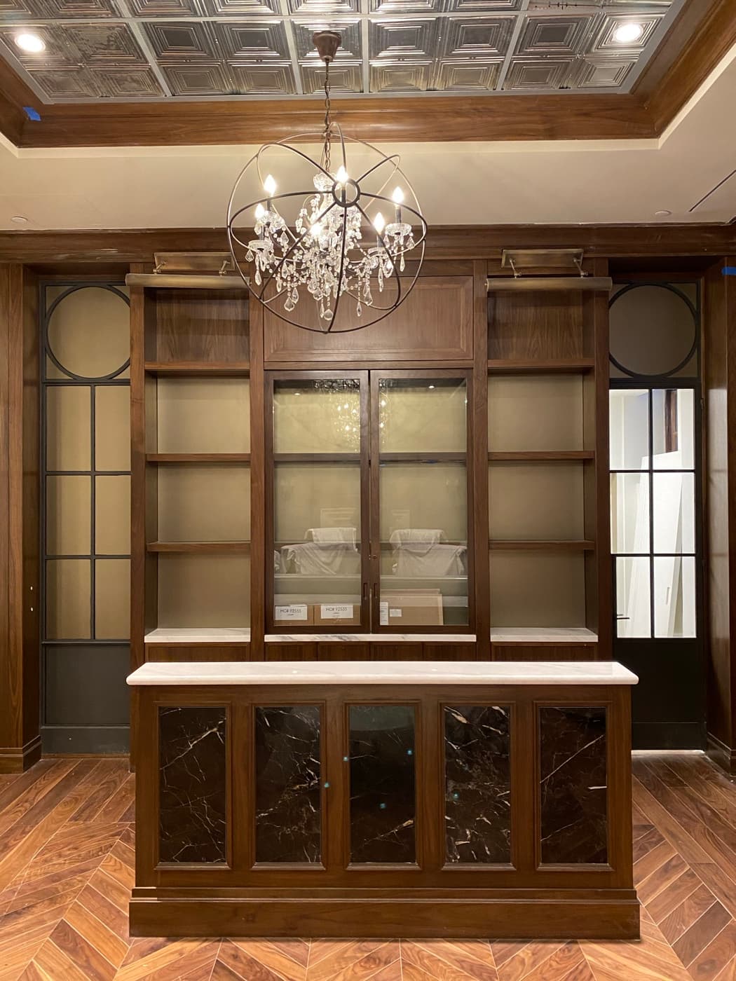 Home bar featuring dark timber built-in cabinetry, stone-accented island, and herringbone timber flooring