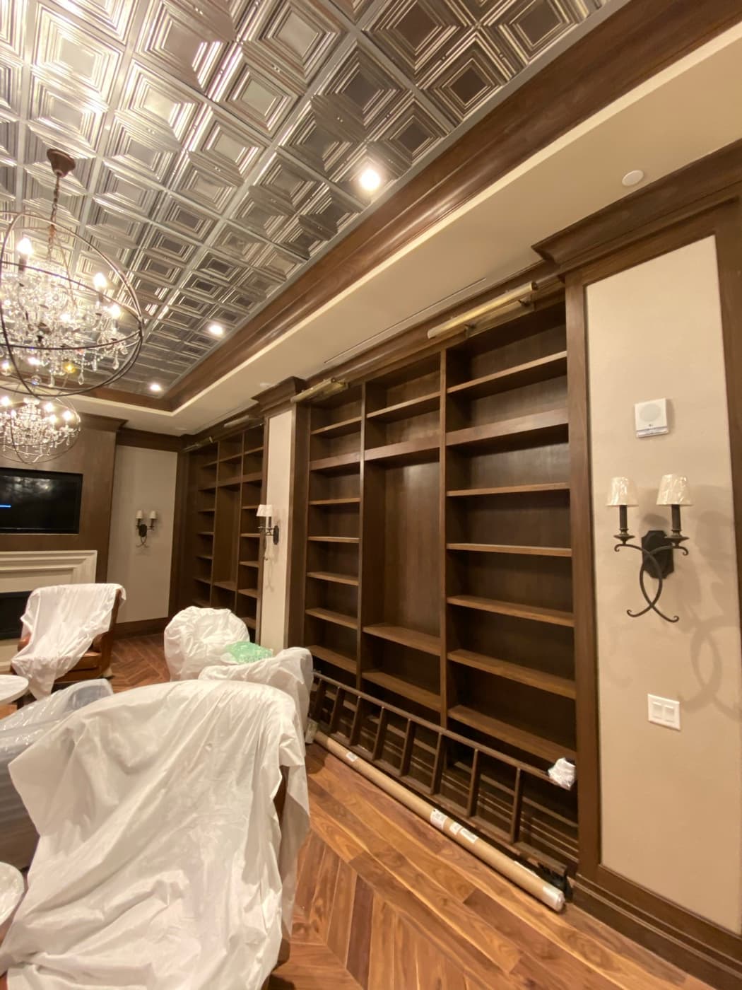 Library with floor-to-ceiling dark timber bookcases, embossed metal ceiling, and chandelier lighting