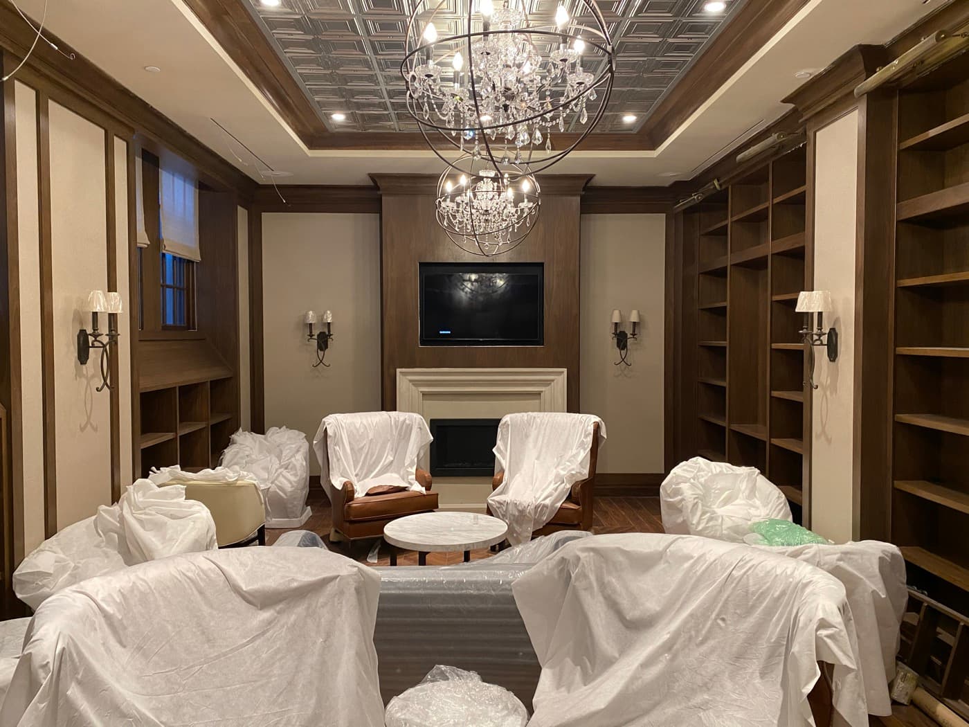Library lounge featuring dark timber built-in bookcases, fireplace panelling, and decorative metal ceiling