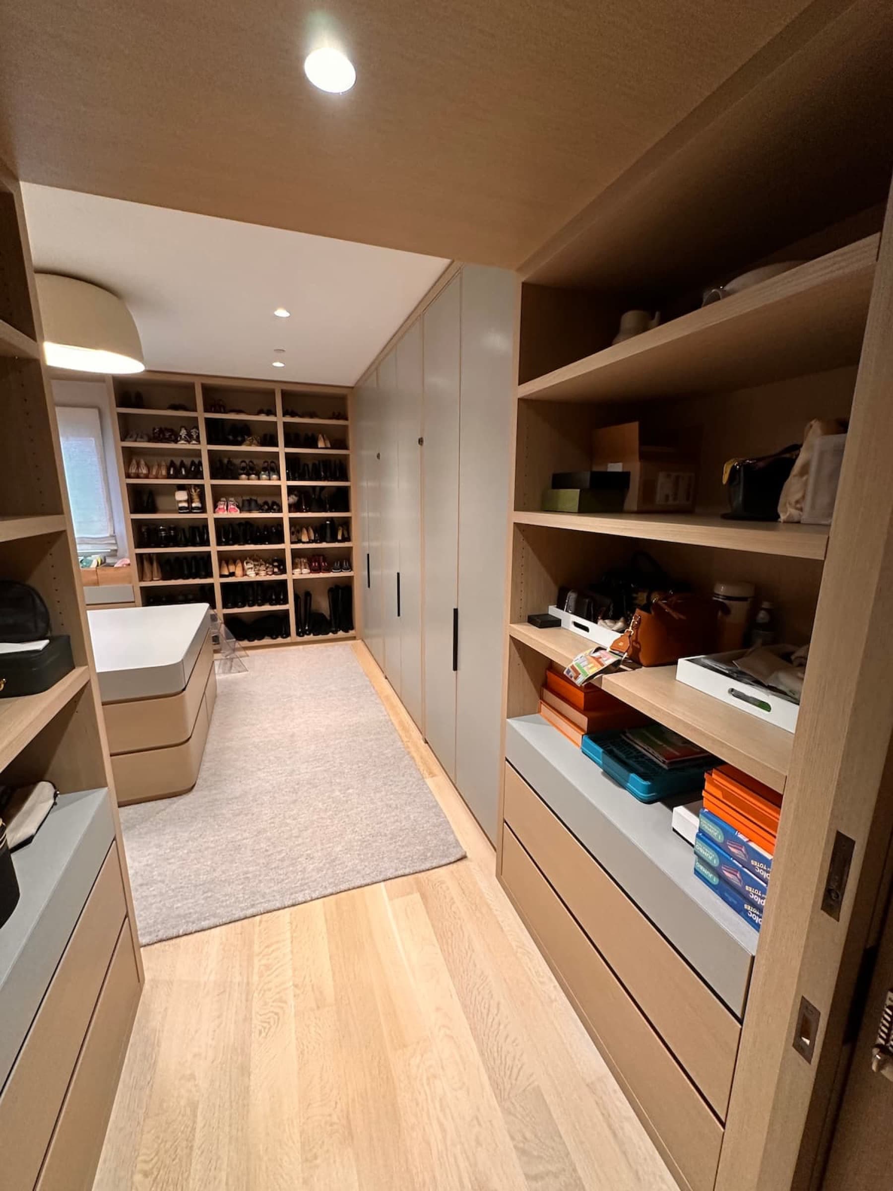 Walk-in dressing room with custom pale timber open shelving, built-in wardrobes, and shoe storage