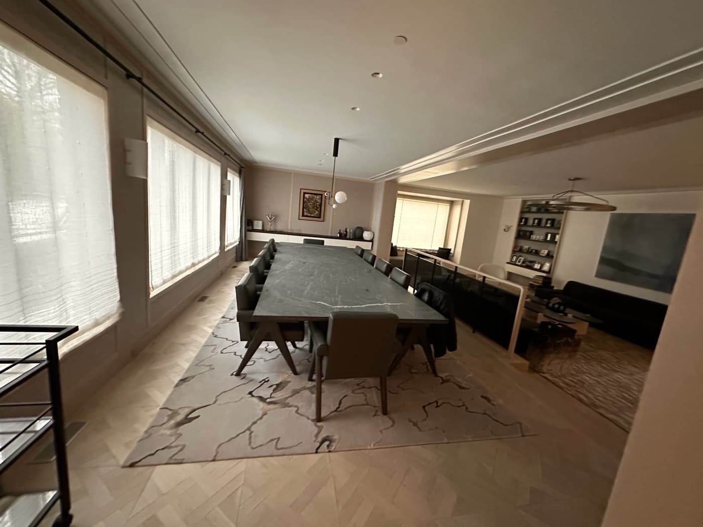 Open-plan dining room with a long dark stone table and pale timber parquet flooring