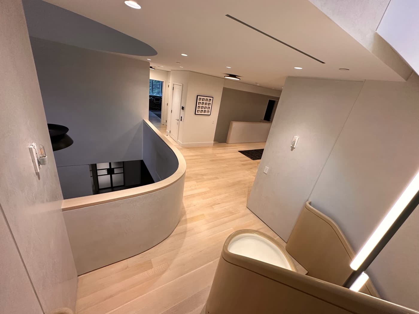 Upper hallway landing with curved balustrade wall overlooking the stairwell and pale timber flooring