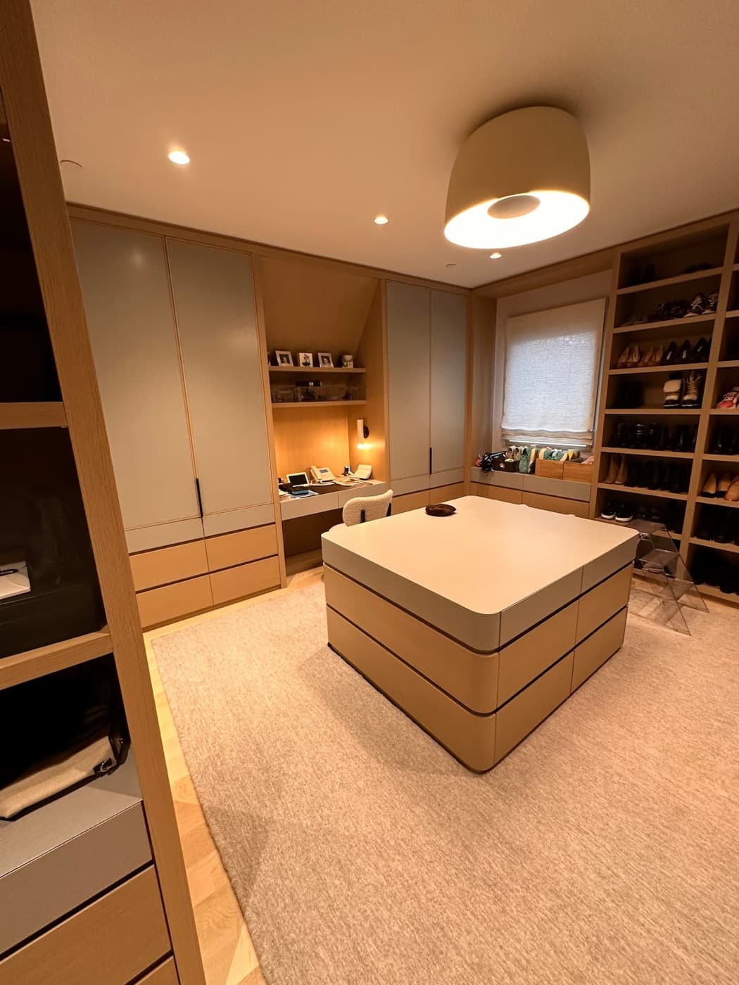 Dressing room with custom light-toned timber wardrobes, integrated desk niche, and central drawer island