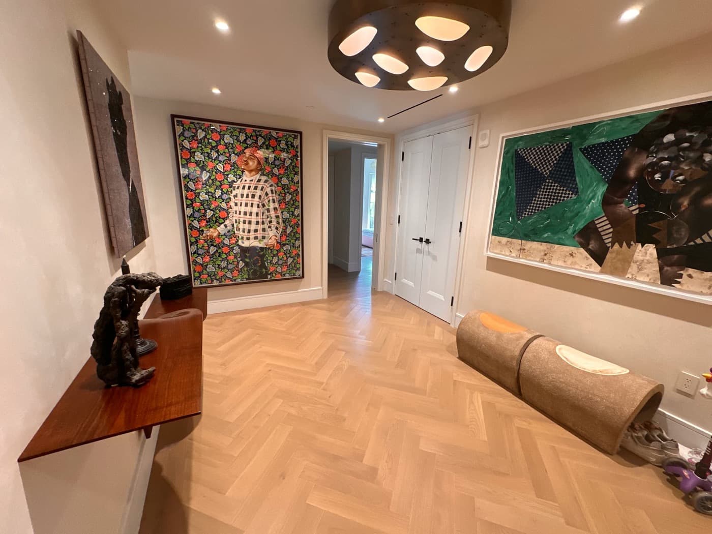 Hallway gallery featuring herringbone timber flooring, white panelled doors, and a bronze ceiling fixture