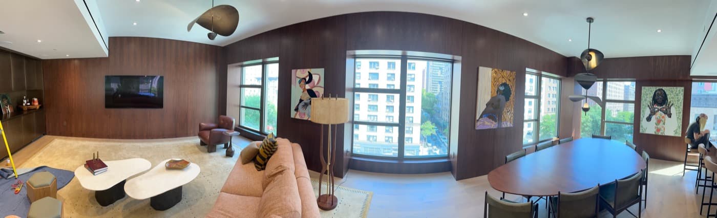 Living and dining space with curved dark timber wall panelling framing multiple large windows