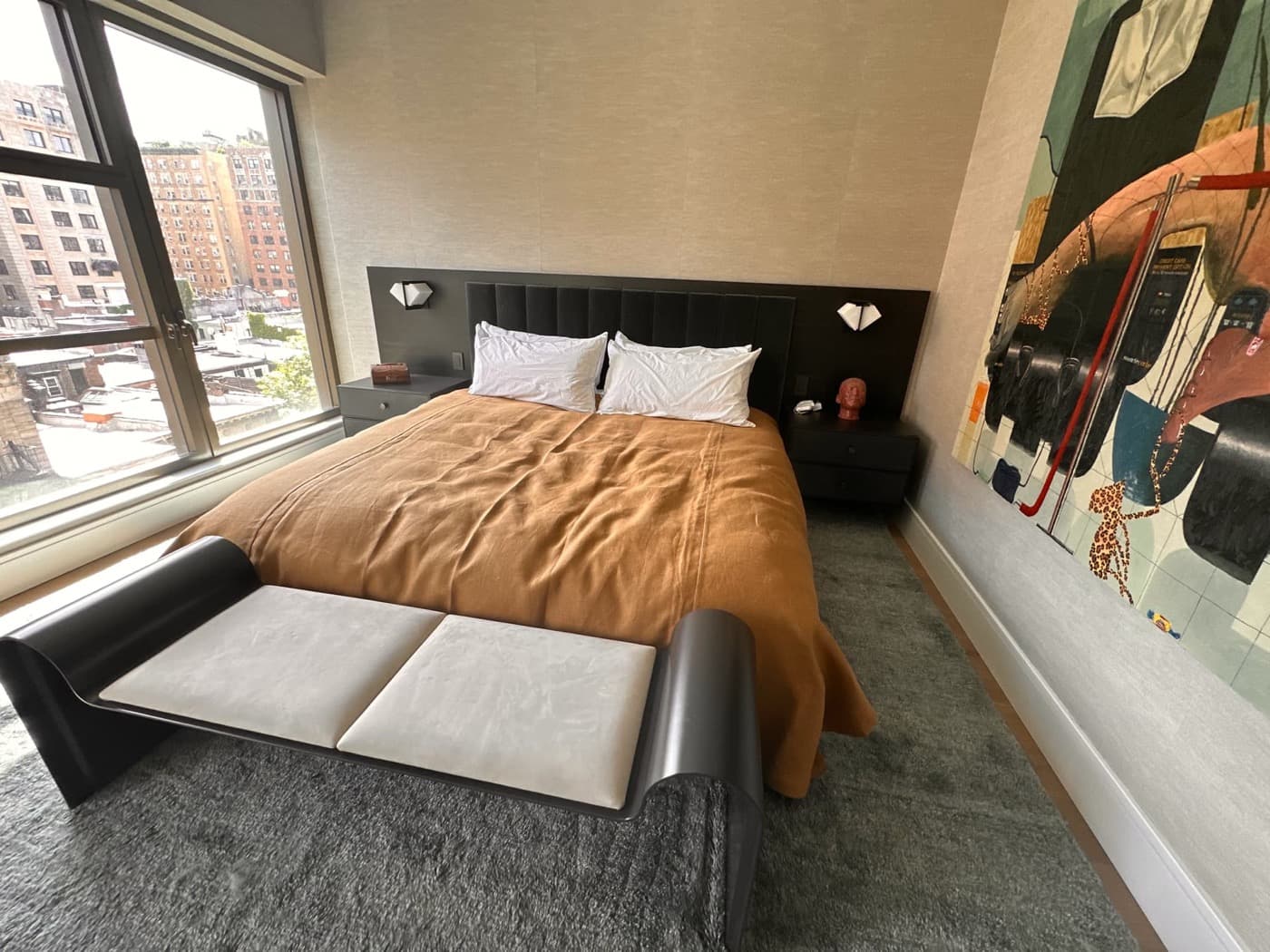 Bedroom with custom dark millwork headboard, integrated bedside tables, and curved upholstered bench