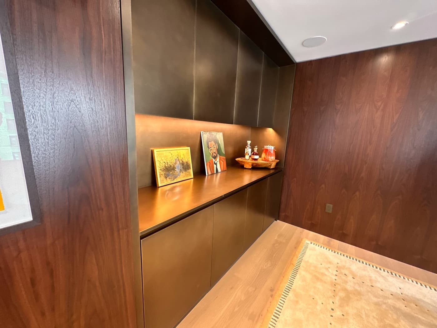 Living space with built-in bronze-toned cabinetry recessed into dark timber wall panelling