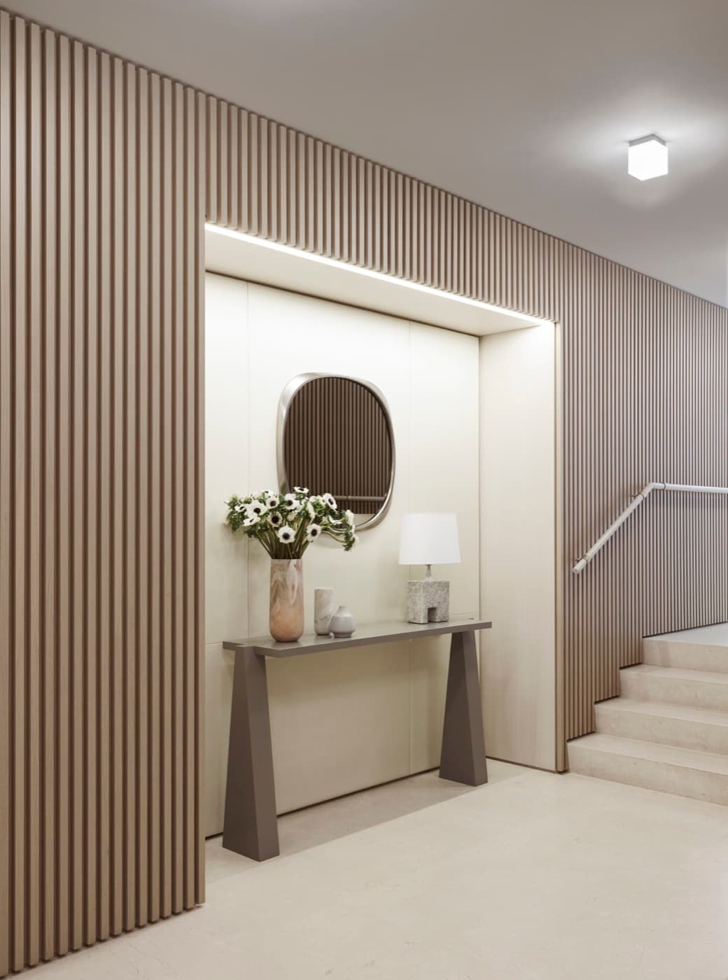 Entryway featuring vertical timber slat wall panelling framing an illuminated recessed niche