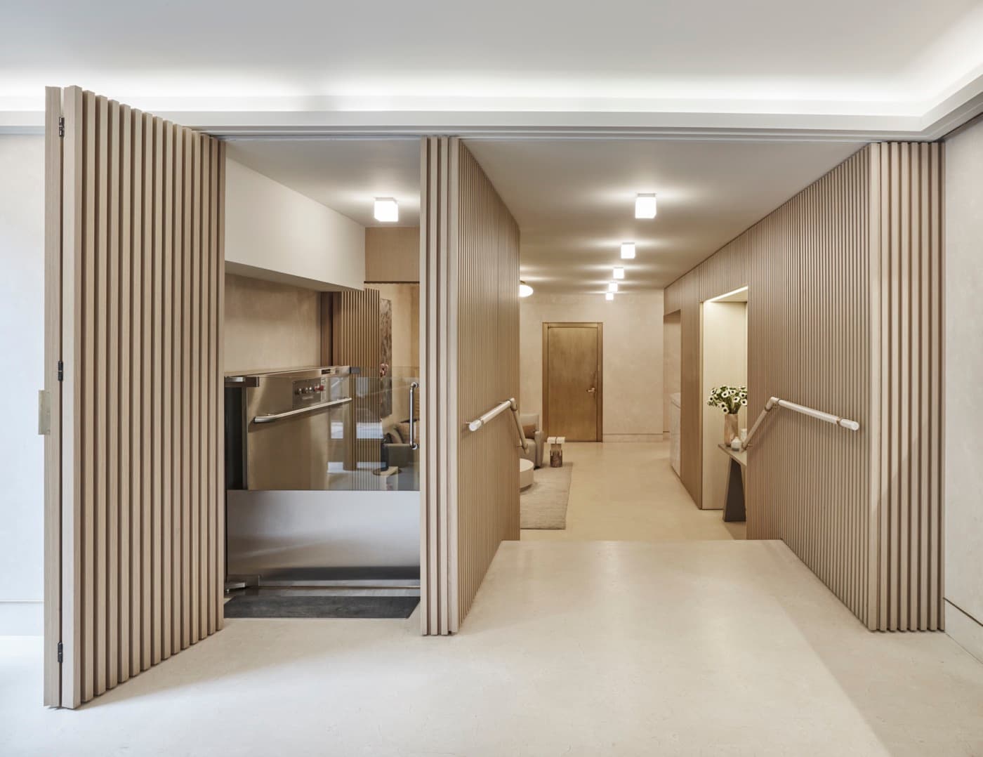 Entry corridor with vertical slatted timber wall panelling, folding screen partitions, and handrails