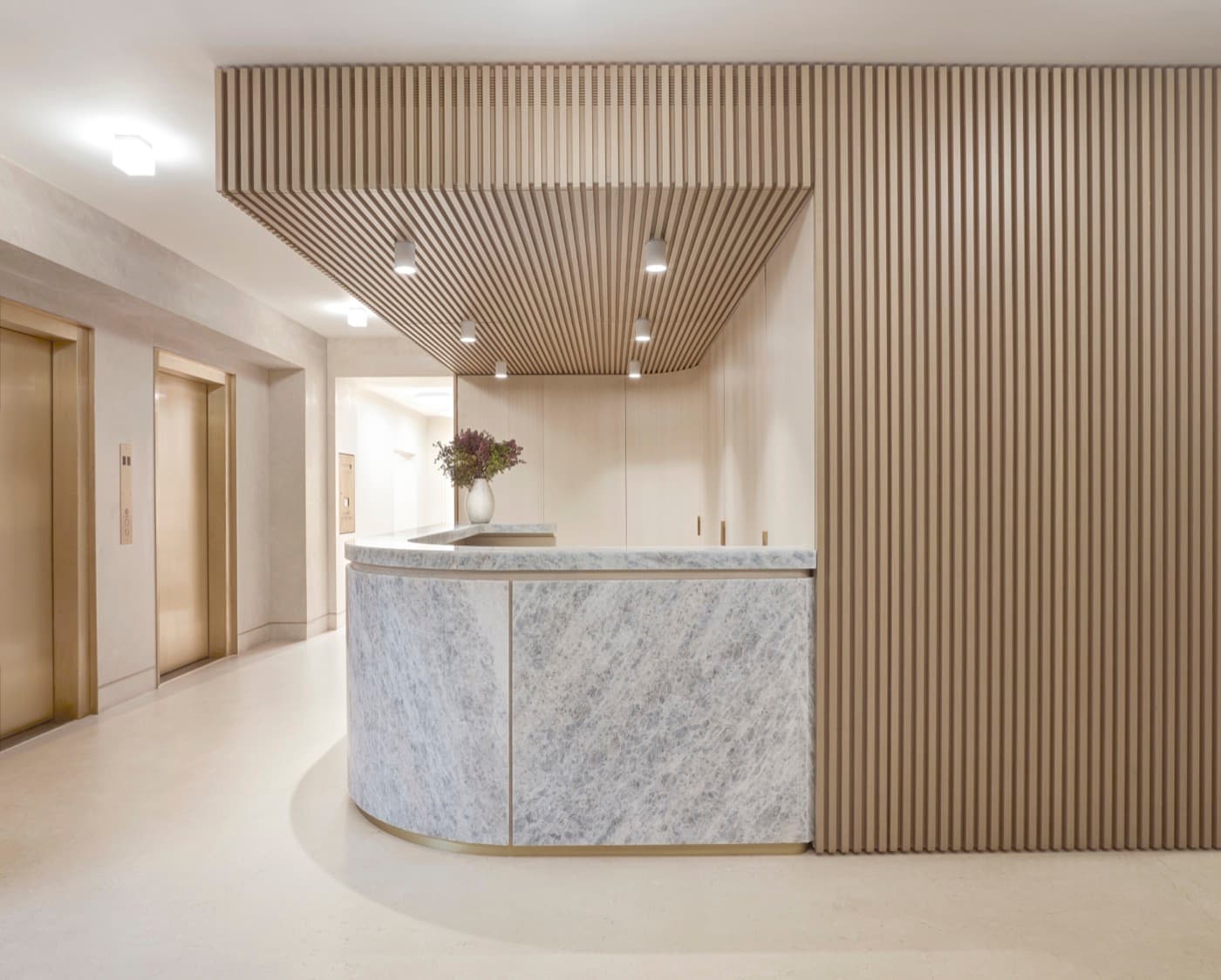 Lobby featuring a curved veined stone reception desk and slatted timber ceiling canopy