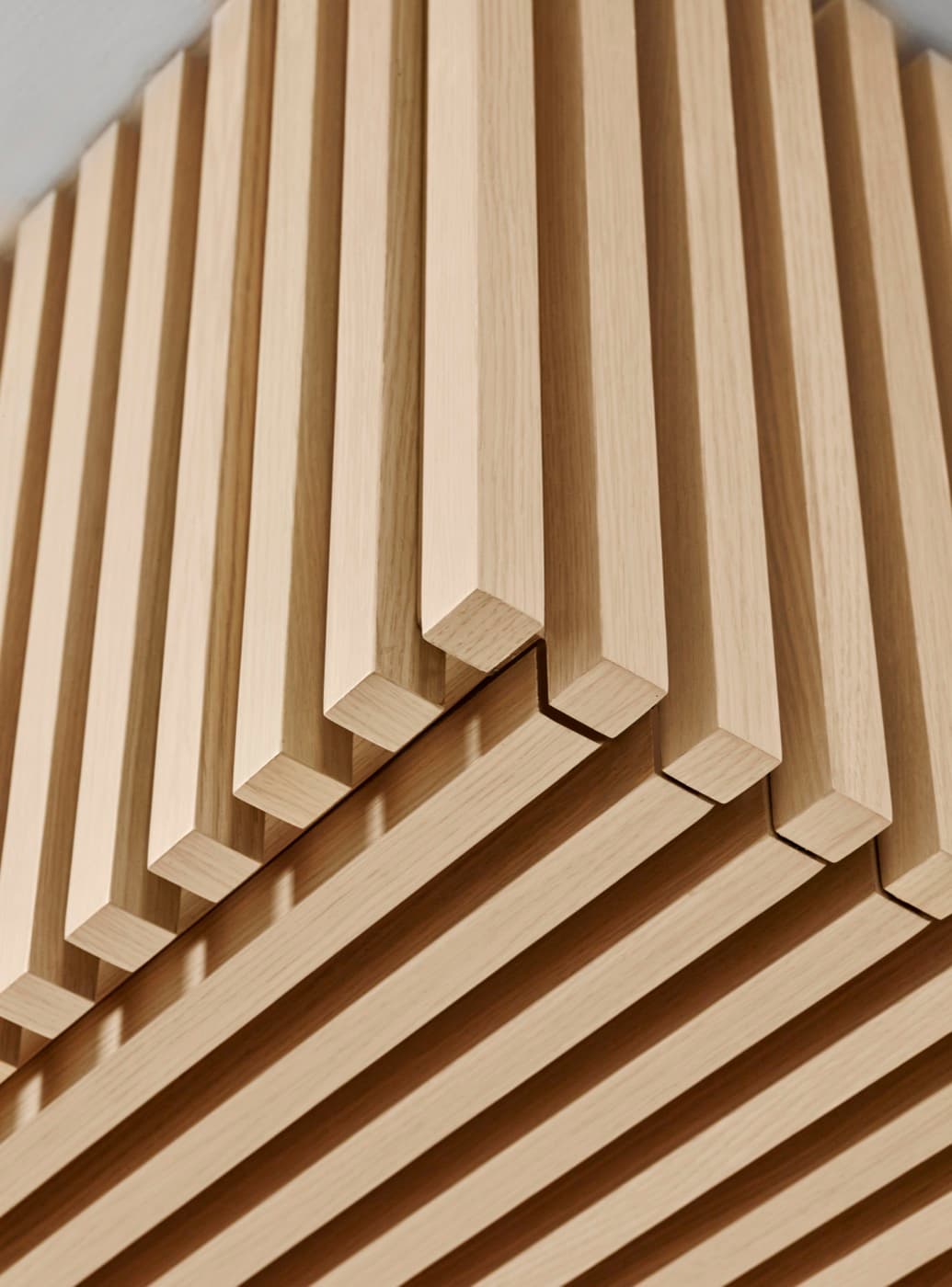 Interior detail of light timber slatted wall panelling with precision corner joinery