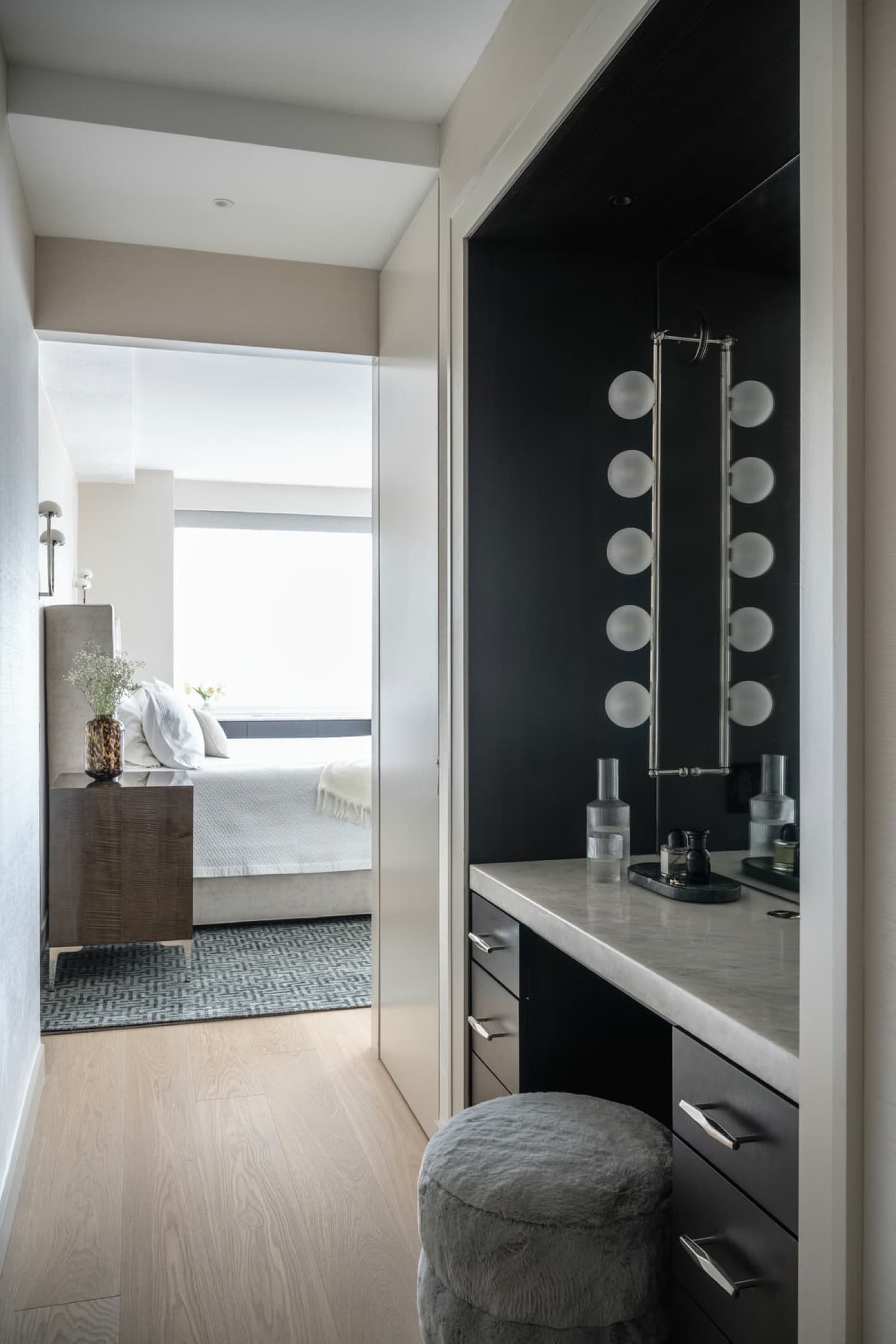 Dressing area featuring a dark built-in vanity with pale stone countertop leading to bedroom