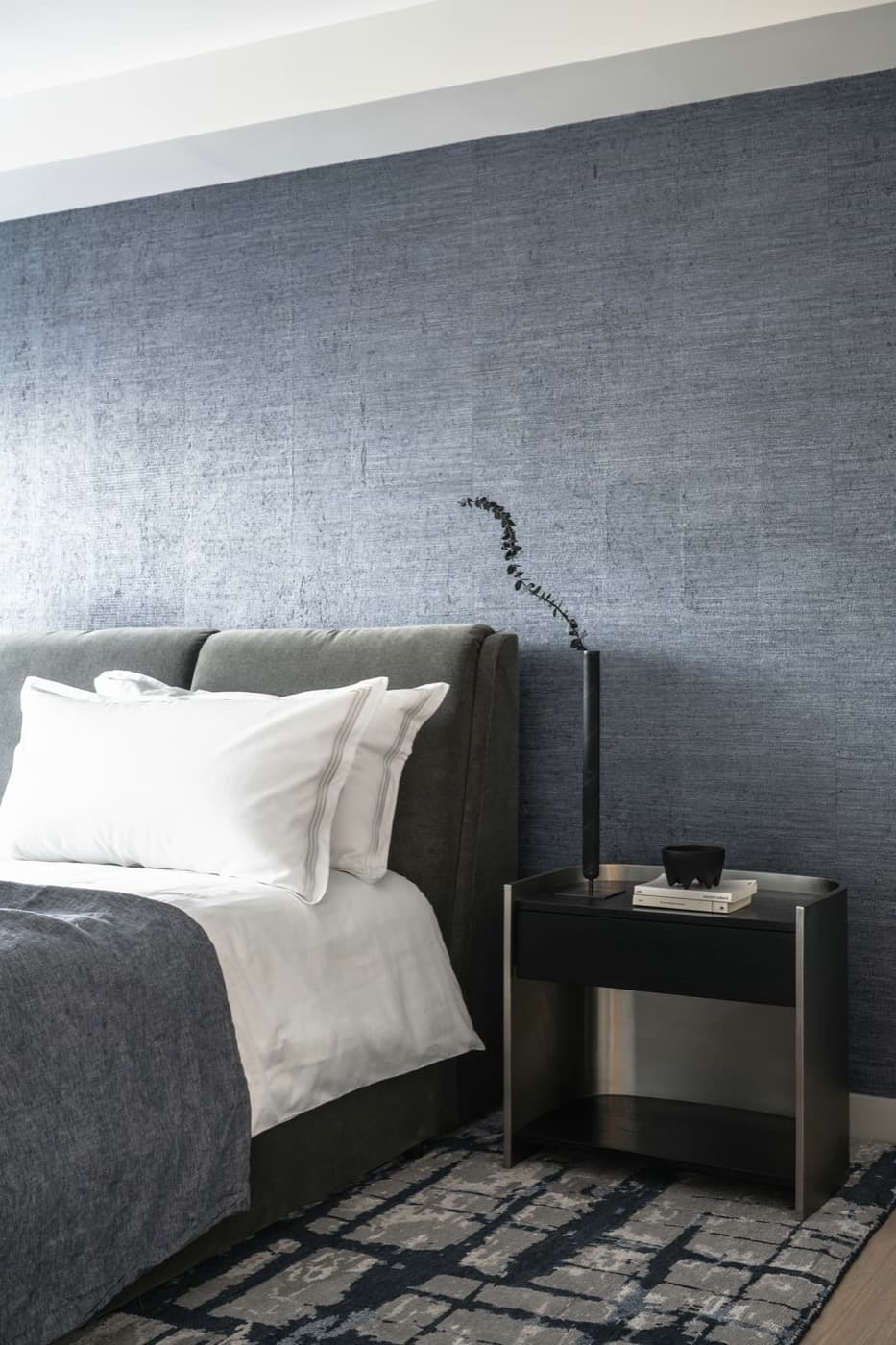 Bedroom featuring textured wall covering behind an upholstered bed and modern nightstand