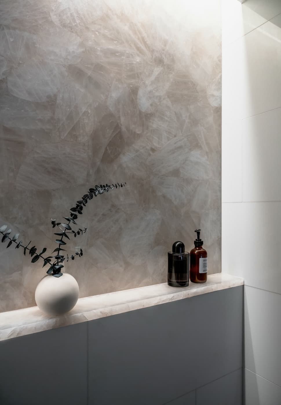 Bathroom feature wall in translucent crystalline stone with matching built-in stone ledge