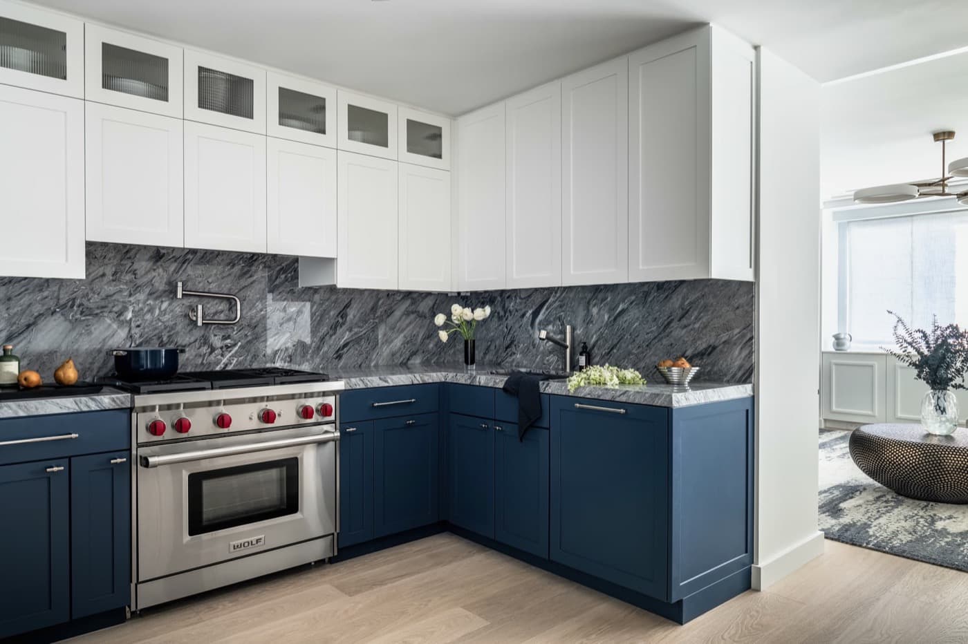 Kitchen with two-tone blue and white cabinetry, dark veined stone backsplash, and matching countertops