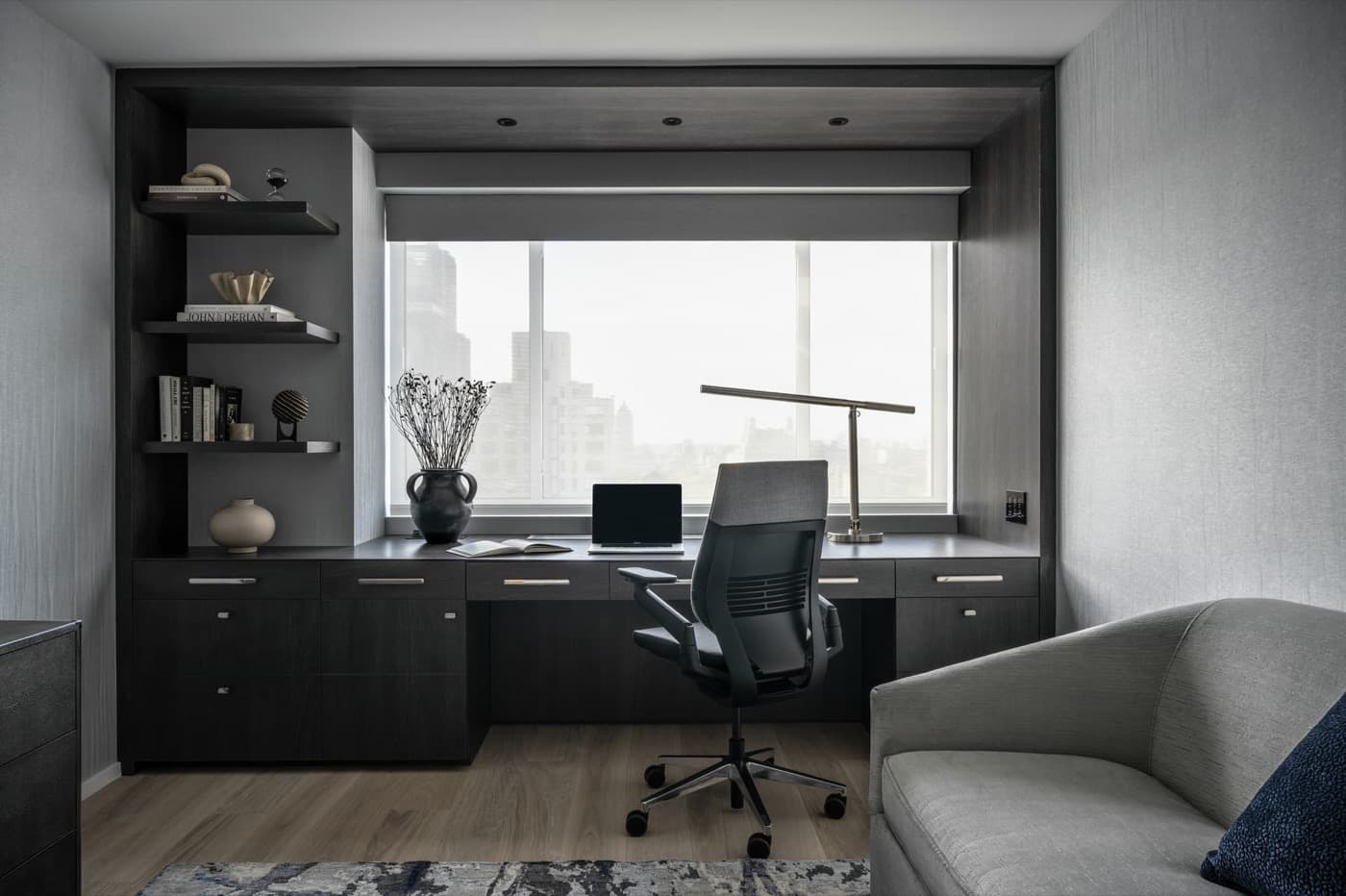 Home office featuring dark-stained timber built-in desk cabinetry, shelving, and integrated window surround