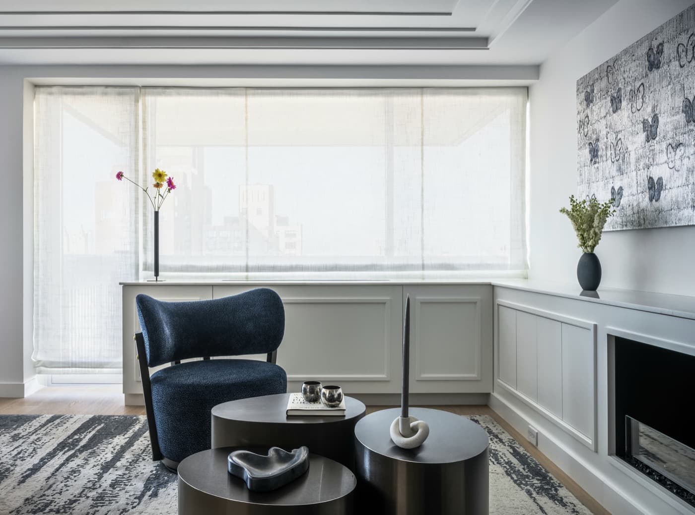 Living room with white paneled millwork wrapping beneath large windows to a fireplace enclosure