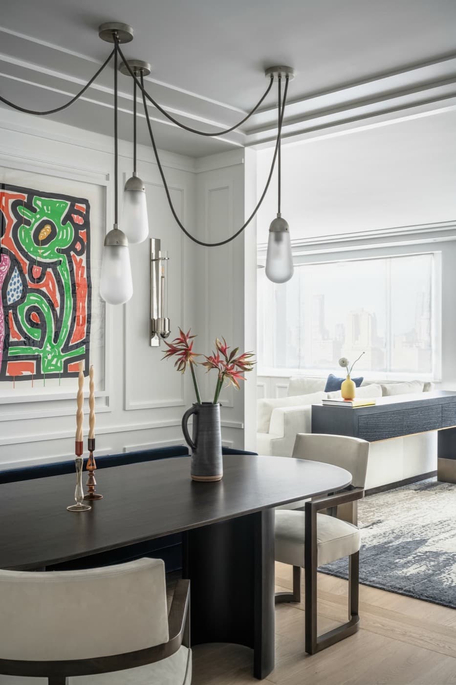 Dining area with classic wall moulding, dark timber dining table, and draped pendant lighting