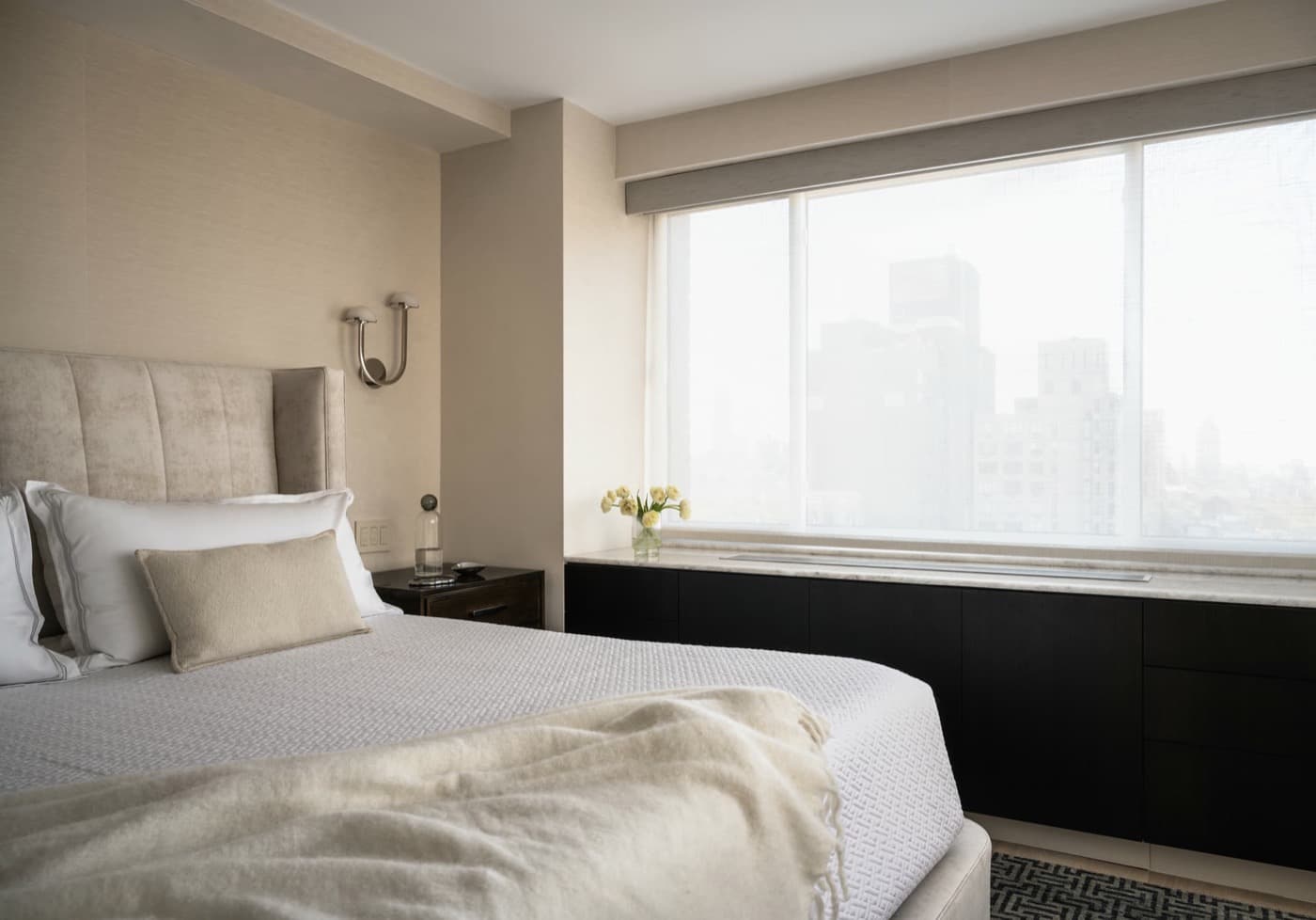 Bedroom featuring built-in dark cabinetry with a pale stone countertop under large windows