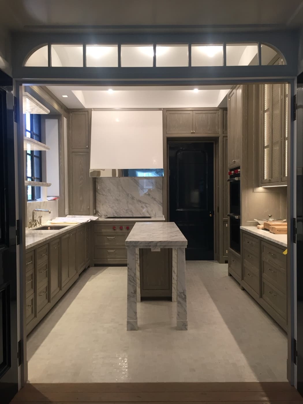 Kitchen with custom timber cabinetry, pale veined stone island, matching countertops, and range hood