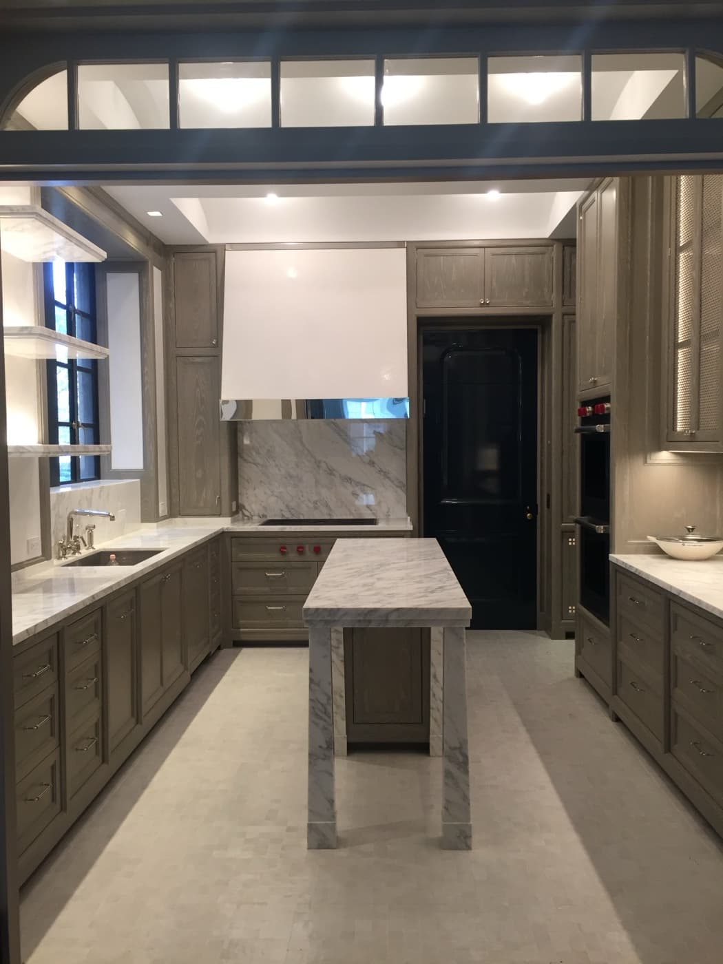 Kitchen with custom grey-toned cabinetry, veined white stone island, and matching countertops