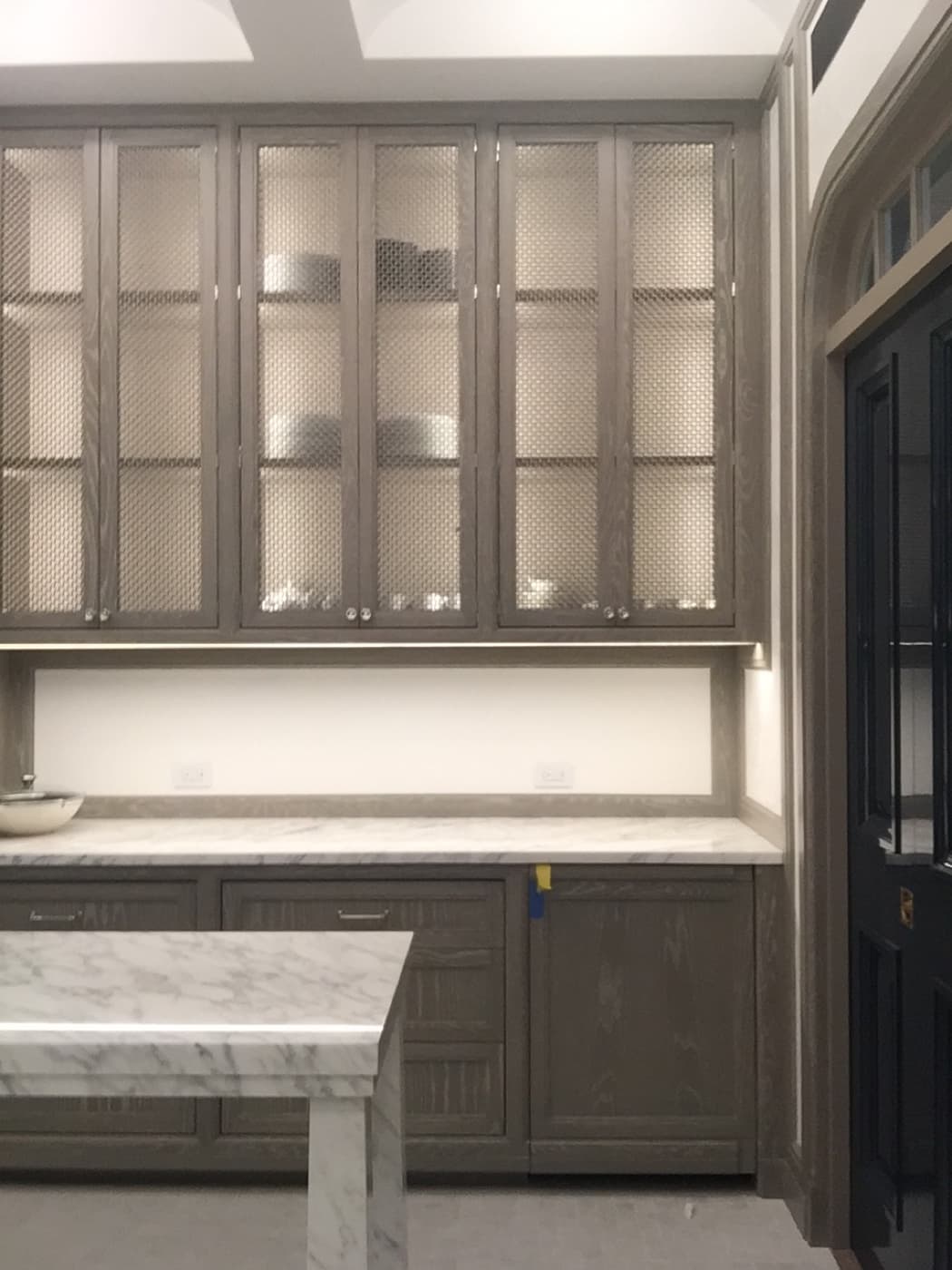 Pantry with custom grey-toned timber cabinetry, wire mesh upper doors, and pale veined stone countertops