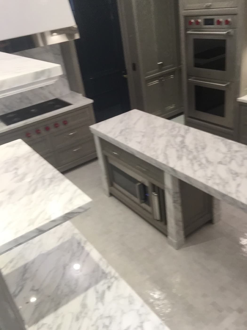 Kitchen with pale veined stone countertops, matching kitchen island, and custom grey cabinetry