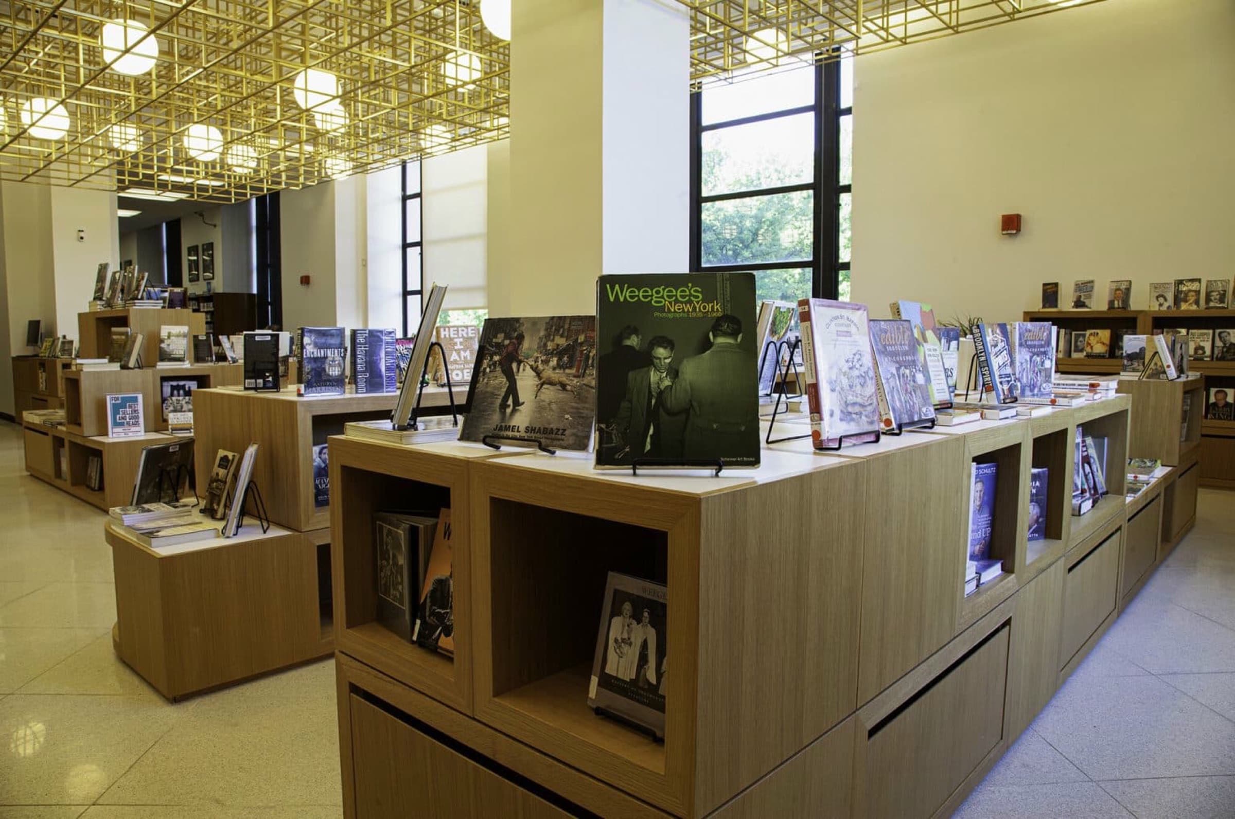 Library featuring custom oak-toned timber book display units beneath a decorative metal ceiling grid