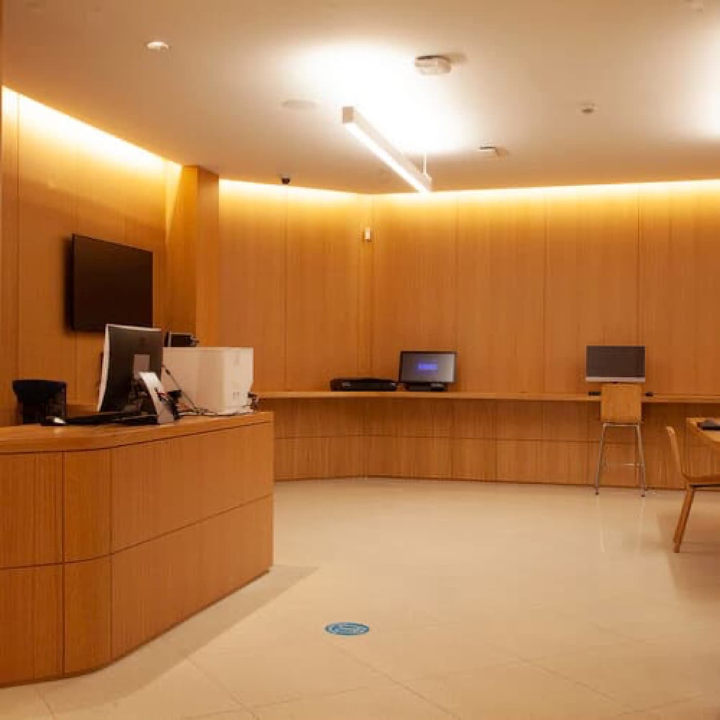 Commercial reception area with warm timber panelling, curved timber desk, and integrated workstations