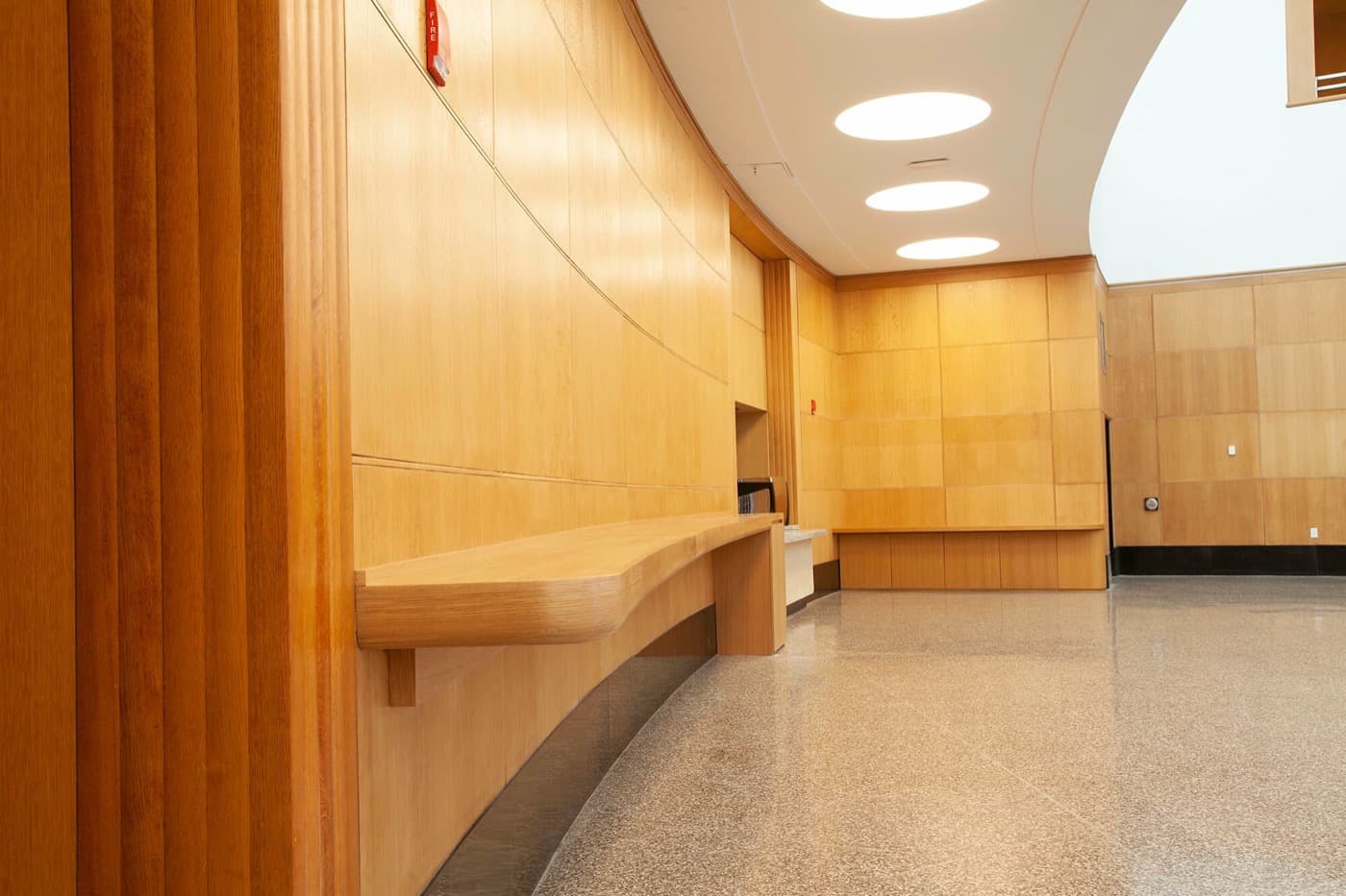 Curved lobby with light timber wall panelling and an integrated cantilevered wooden counter