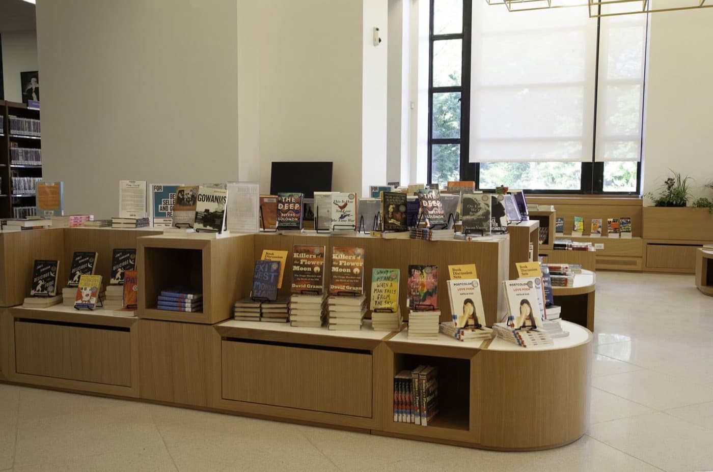 Library interior with custom tiered light timber display units and open cubby shelving