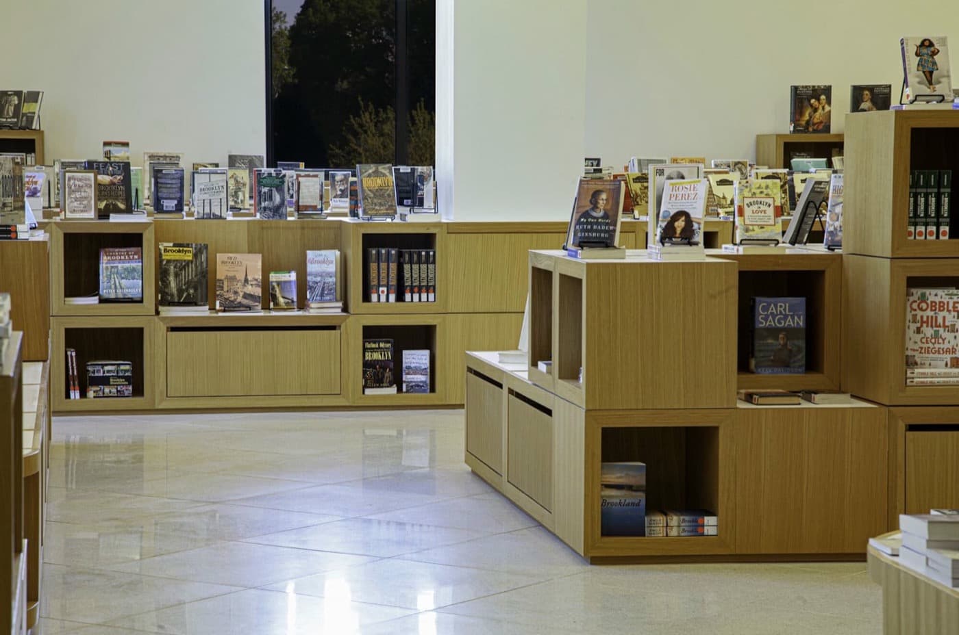 Library interior with modular light timber display shelving and polished tile flooring