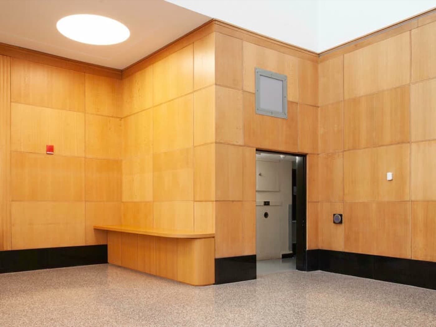 Lobby featuring honey-toned timber wall panelling, built-in timber counter, and polished terrazzo flooring