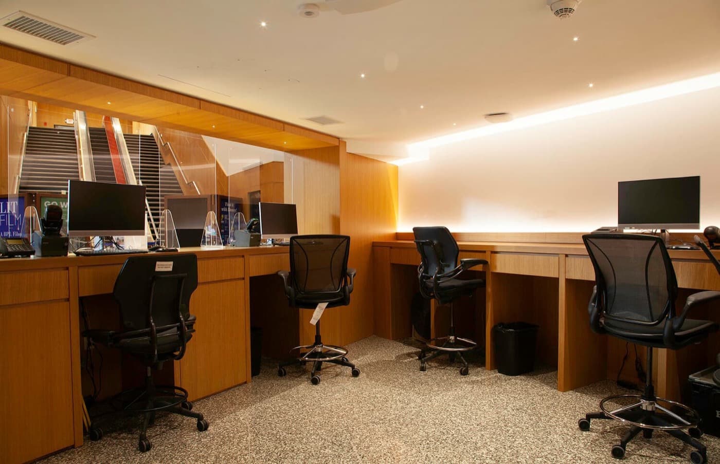 Commercial office area with custom warm timber built-in desks, workstations, and glass partition screens