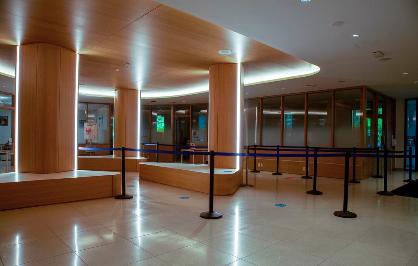 Commercial lobby featuring curved timber-clad columns, matching built-in benches, and illuminated wood ceiling